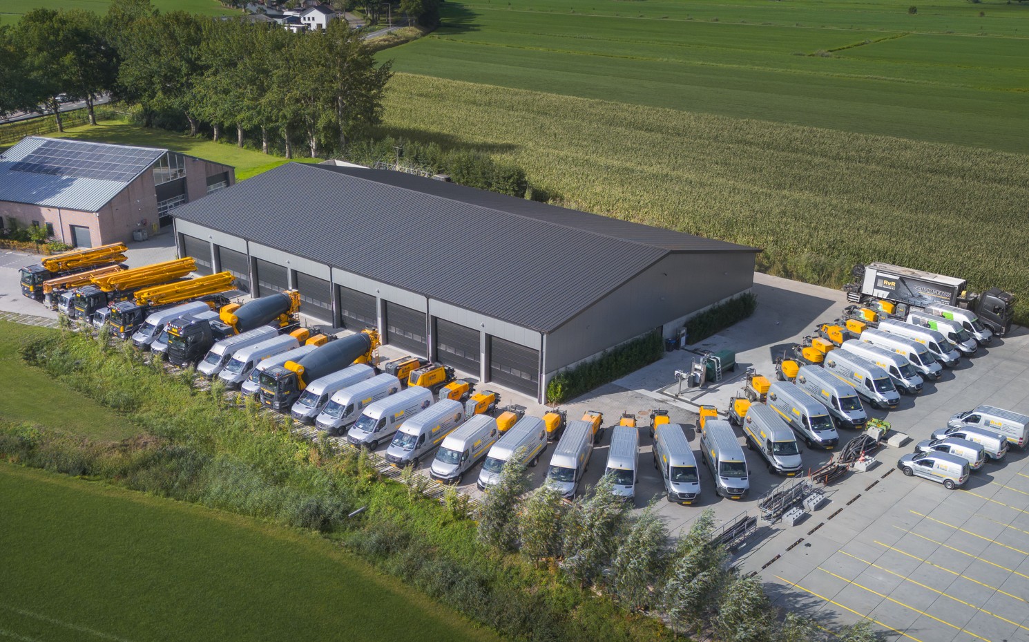 Luchtfoto van het RvR pand met al het materieel, betonpompen, mixers en bedrijfsbussen
